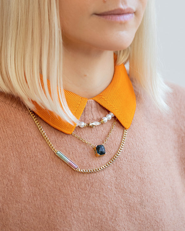Photo of model wearing a light pink sweater with the Union Pearl, Awareness, and the Identity Chain Necklace.