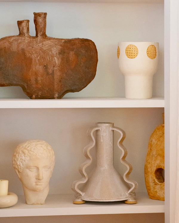 Sculptures, vases and objects displayed on white book shelf.