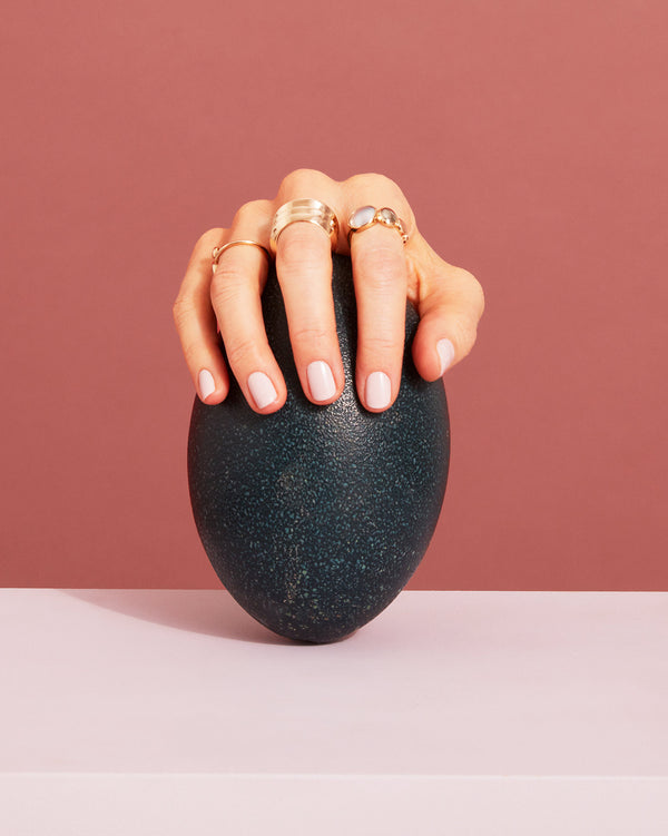 Photo of hand wearing rings from the Trinity Collection holding an ostrich egg