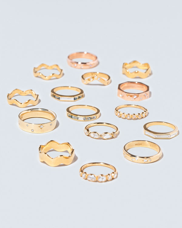 Group of Mociun Gemstone Wedding Bands and Stacking Rings of varying styles and gemstones on light color surface.