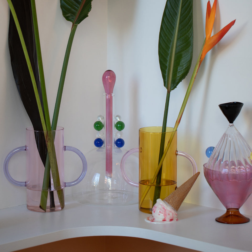 Gifts for your Friend Collection items including colorful glassware, a replica of spilled ice crea, on a white shelf.