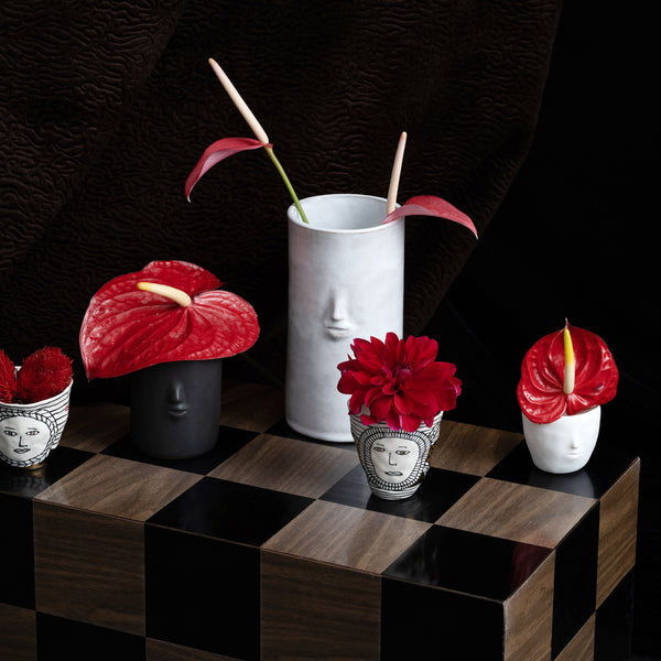 Photo of a mix of tumblers and vases featuring faces on a black background. 