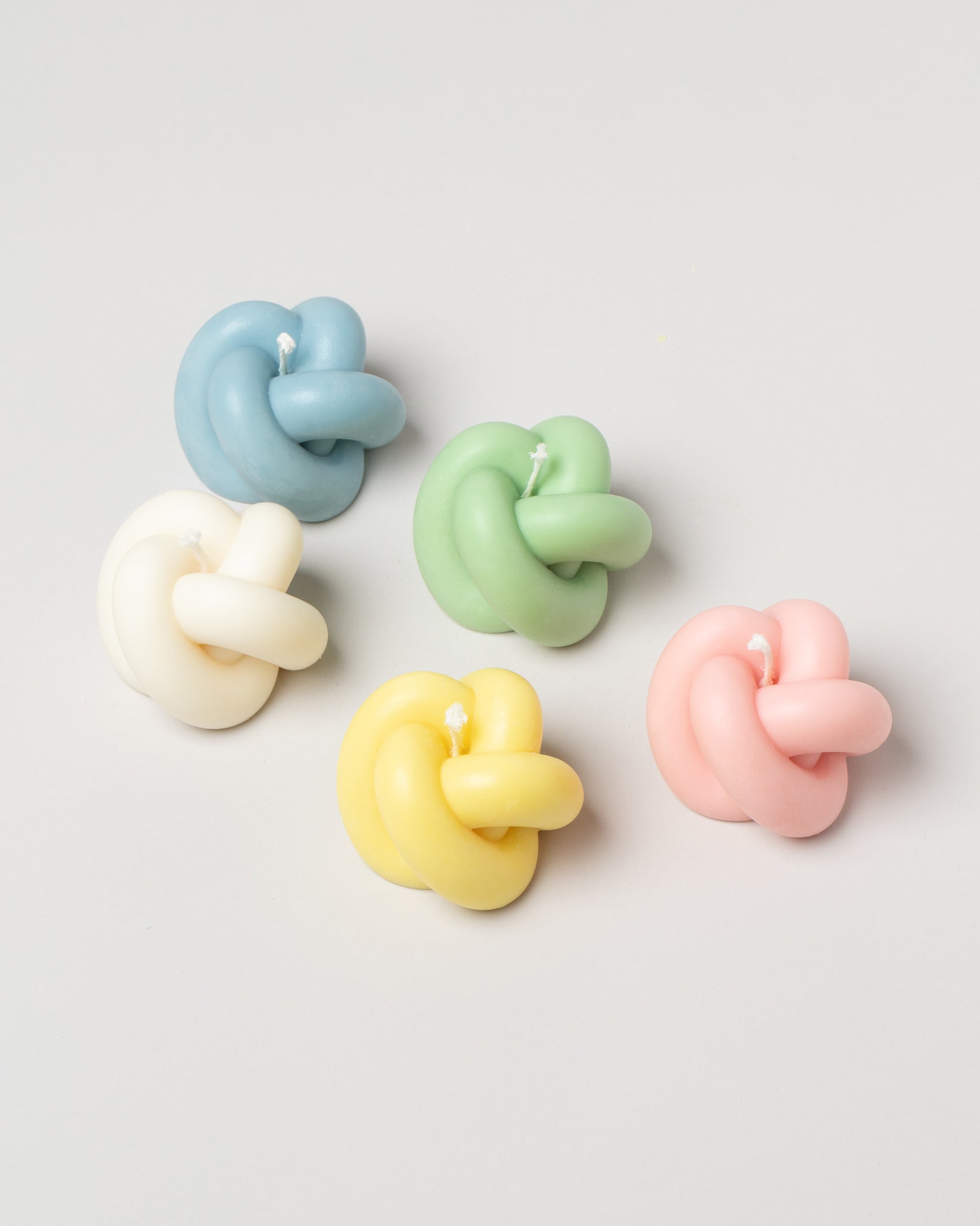 Special Interest Goods Collection Knot Candles in various pastels, on a neutral-light background.
