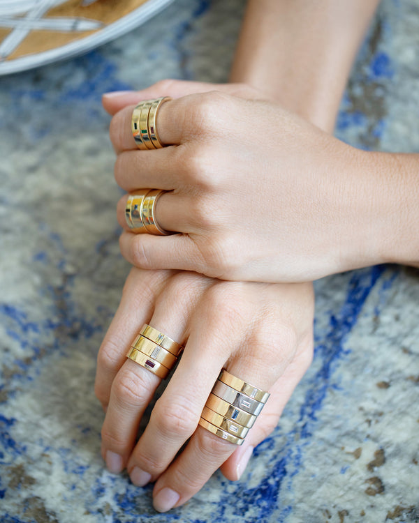 Photo of model's hands wearing all widths of the Piet Bands with different gemstones.