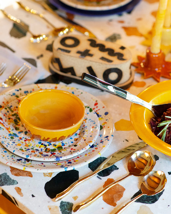 Photo of a table setting with a mix of plates and bowls by Del Monaco on multi color background