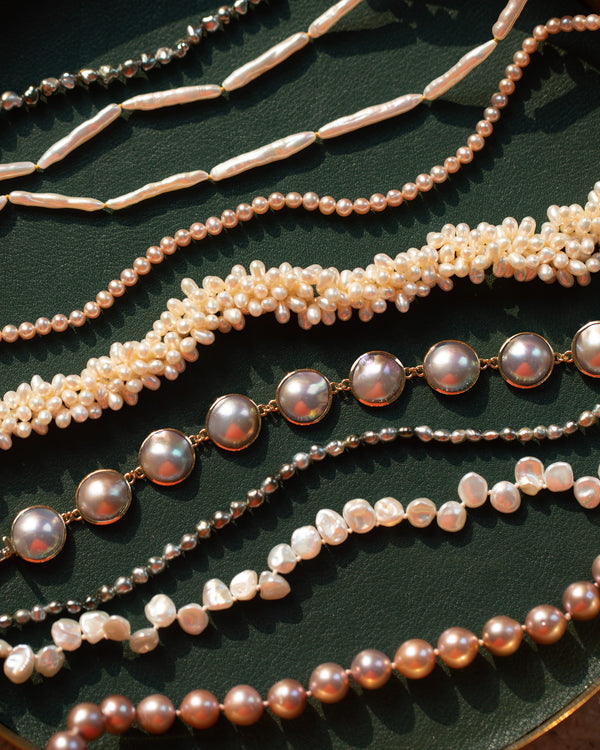 Mociun Collection Pearl Necklaces and Bracelets on a green leather surface.