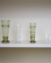 Styled image featuring the Bollenglass Design Clear Petite Spiral Tumbler, Green Petite Spiral Tumbler, Clear Small Spiral Tumbler and Clear Liquor Glass.