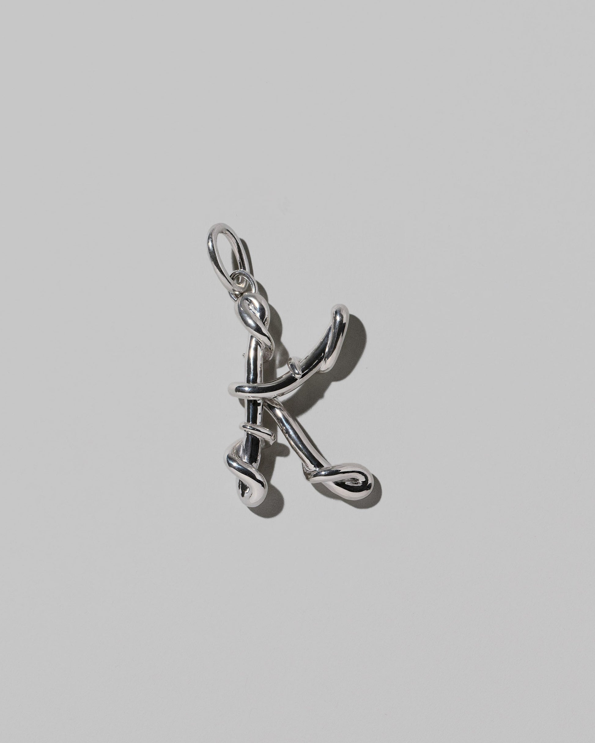 CRZM Sterling Silver Letter K Bag Charm on light color background.