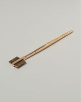 View from the side of the Pearce Objects Cast Bronze Eyebrow Brush on light color background.