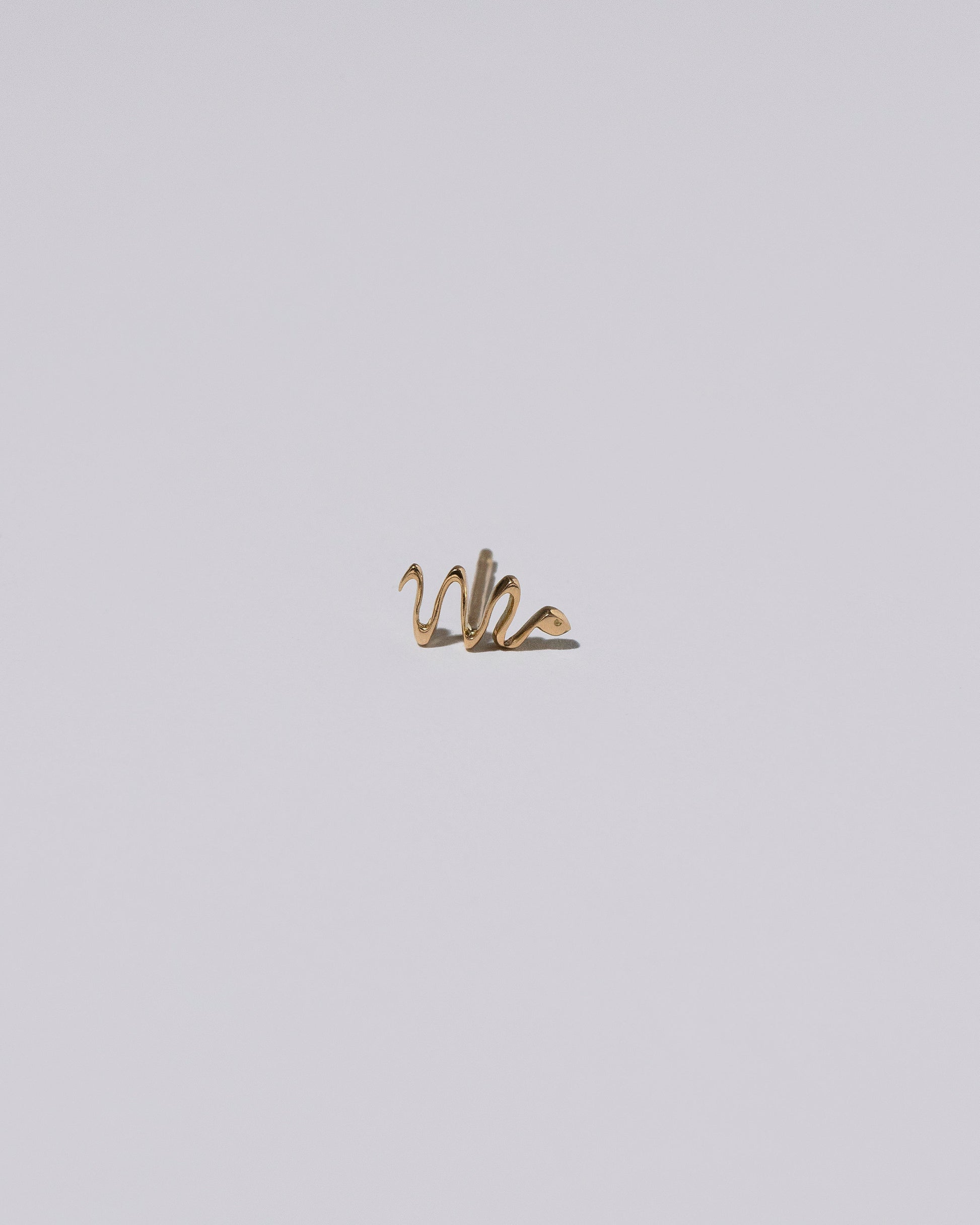 Gold Right Snake Talisman Stud Earring Single on light color background.