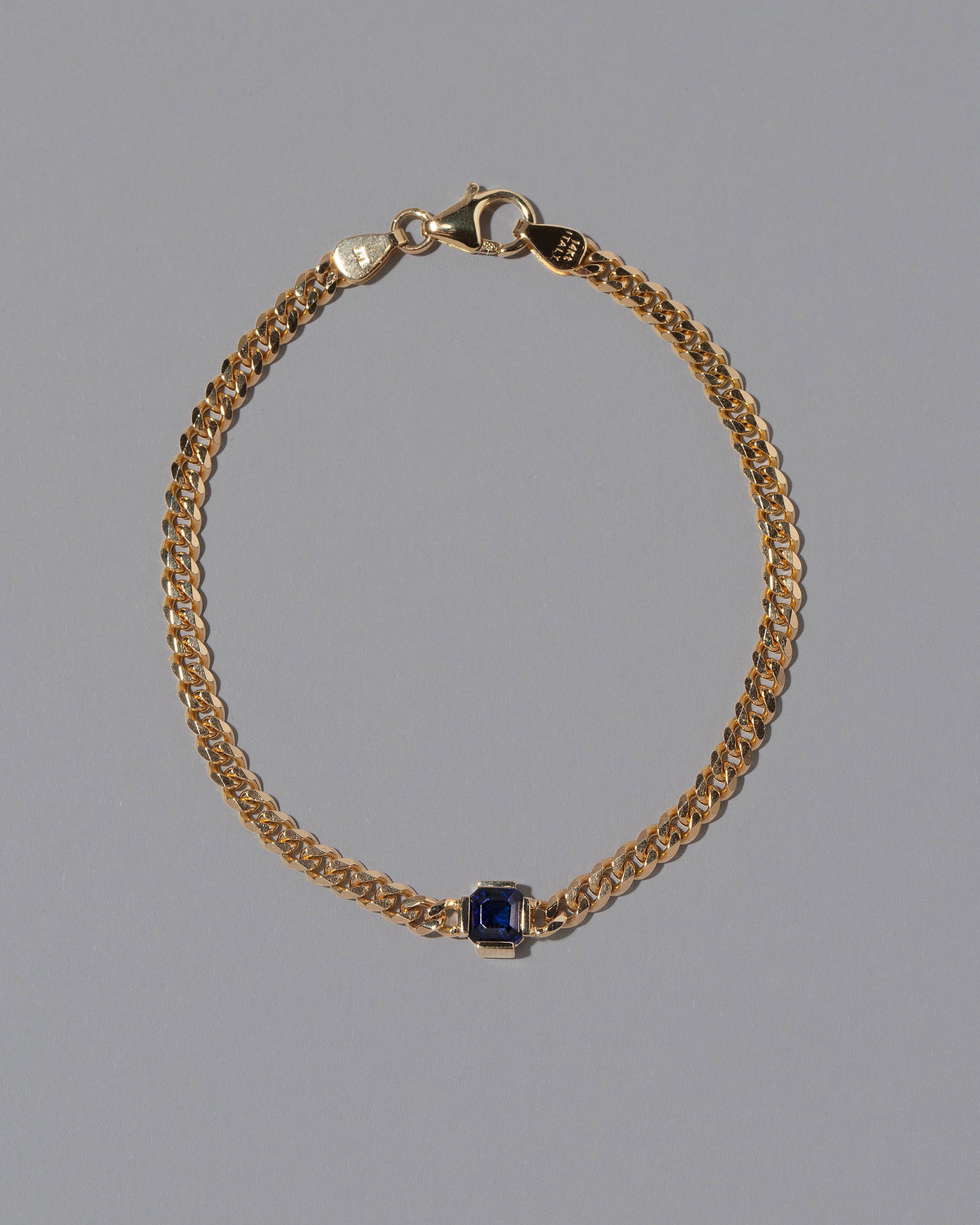 Gold Blue Sapphire Fold Bracelet on grey color background.