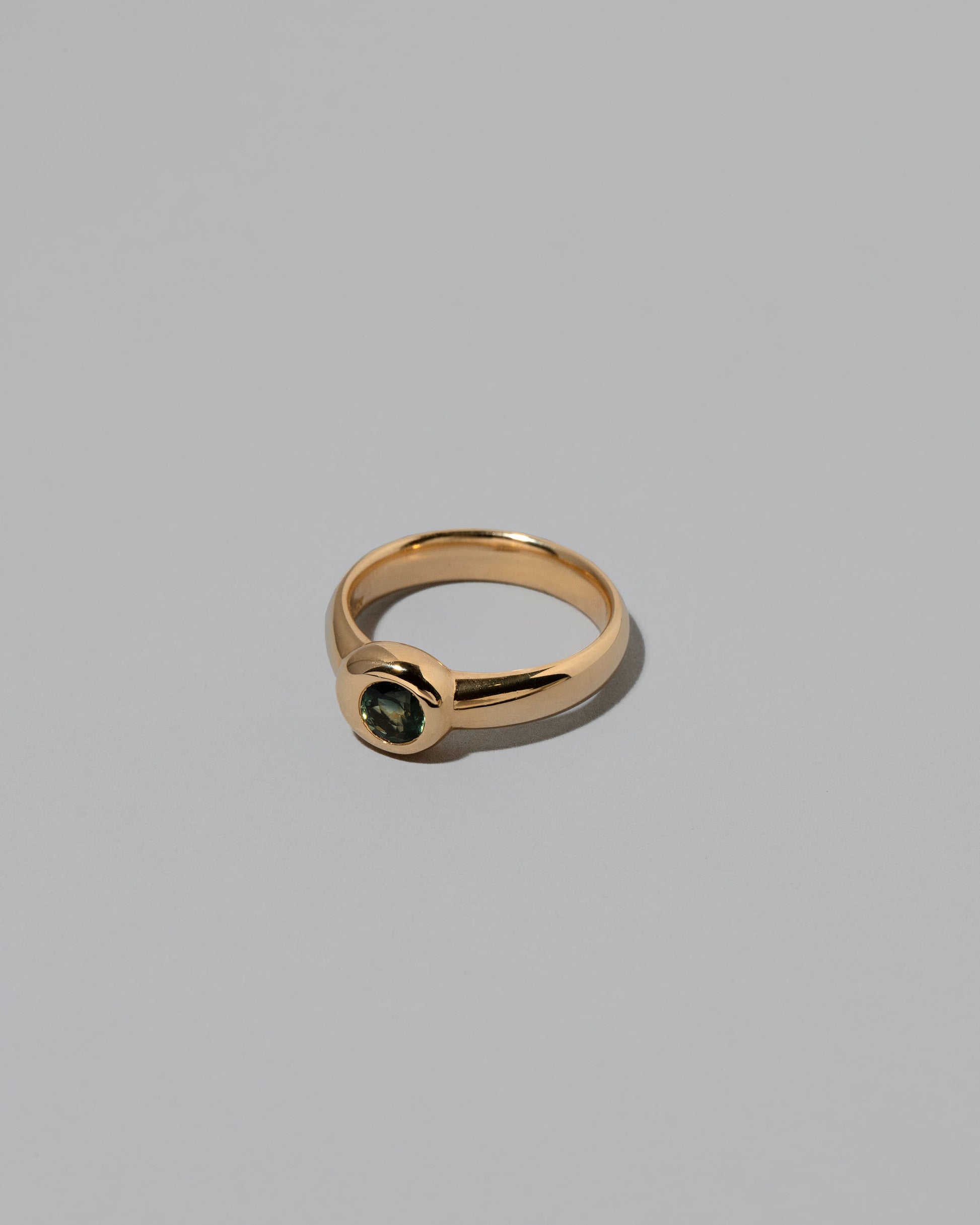 View from the side of the Green Sapphire Level Ring on light color background.