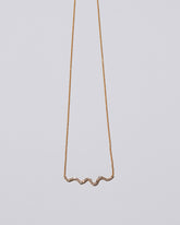 Closeup detail of the White Diamond Ripple Wave Necklace on light color background.