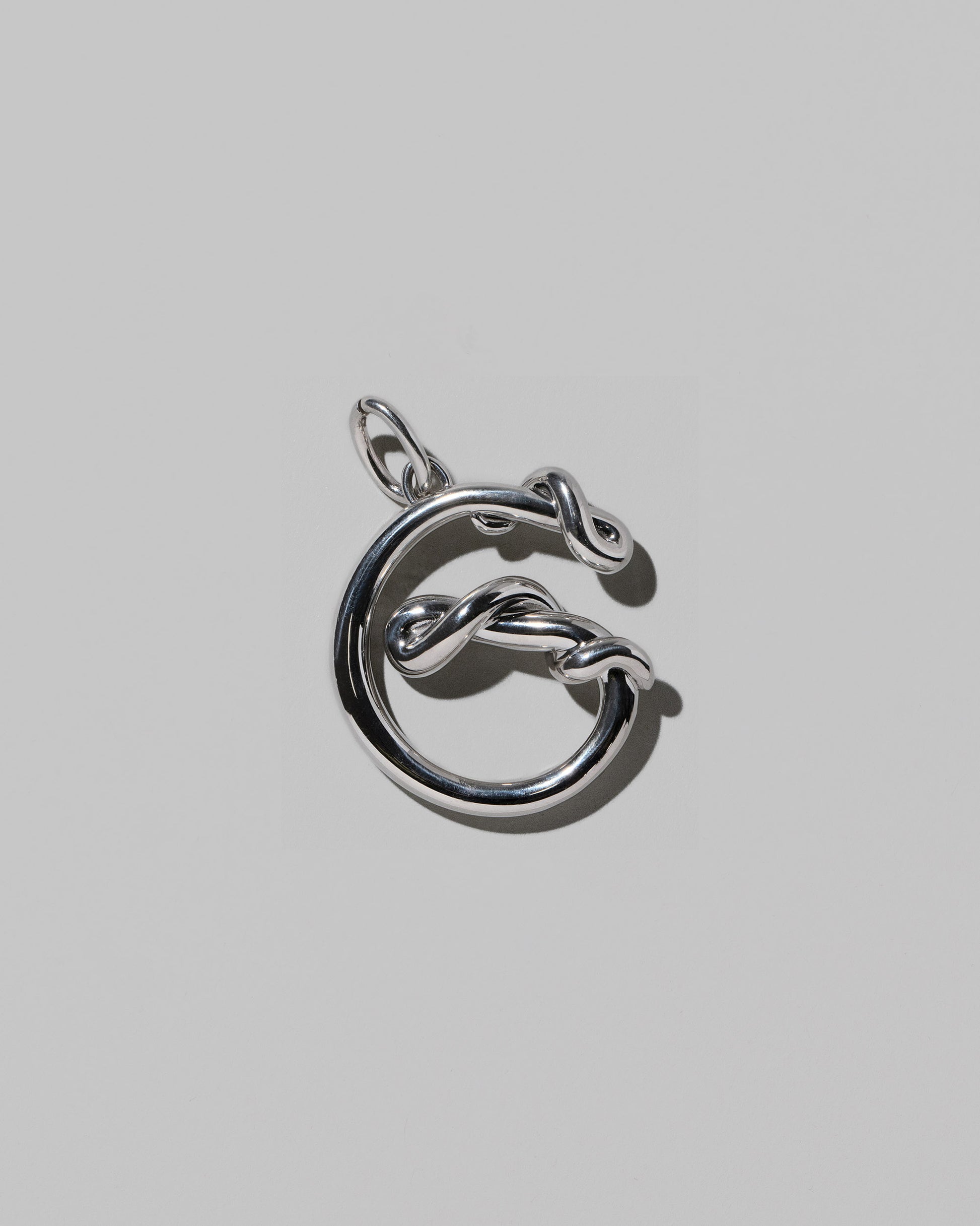 CRZM Large Letter G Charm set in sterling silver on light color background.