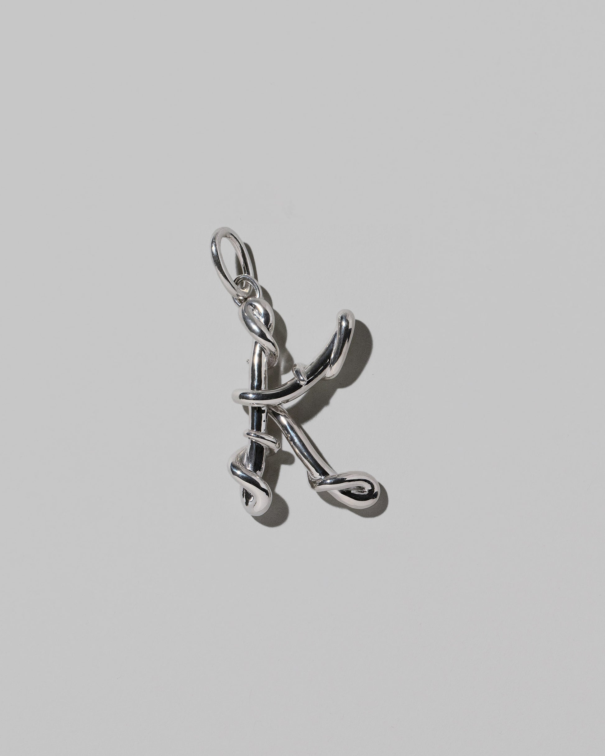 CRZM Large Letter K Charm set in sterling silver on light color background.
