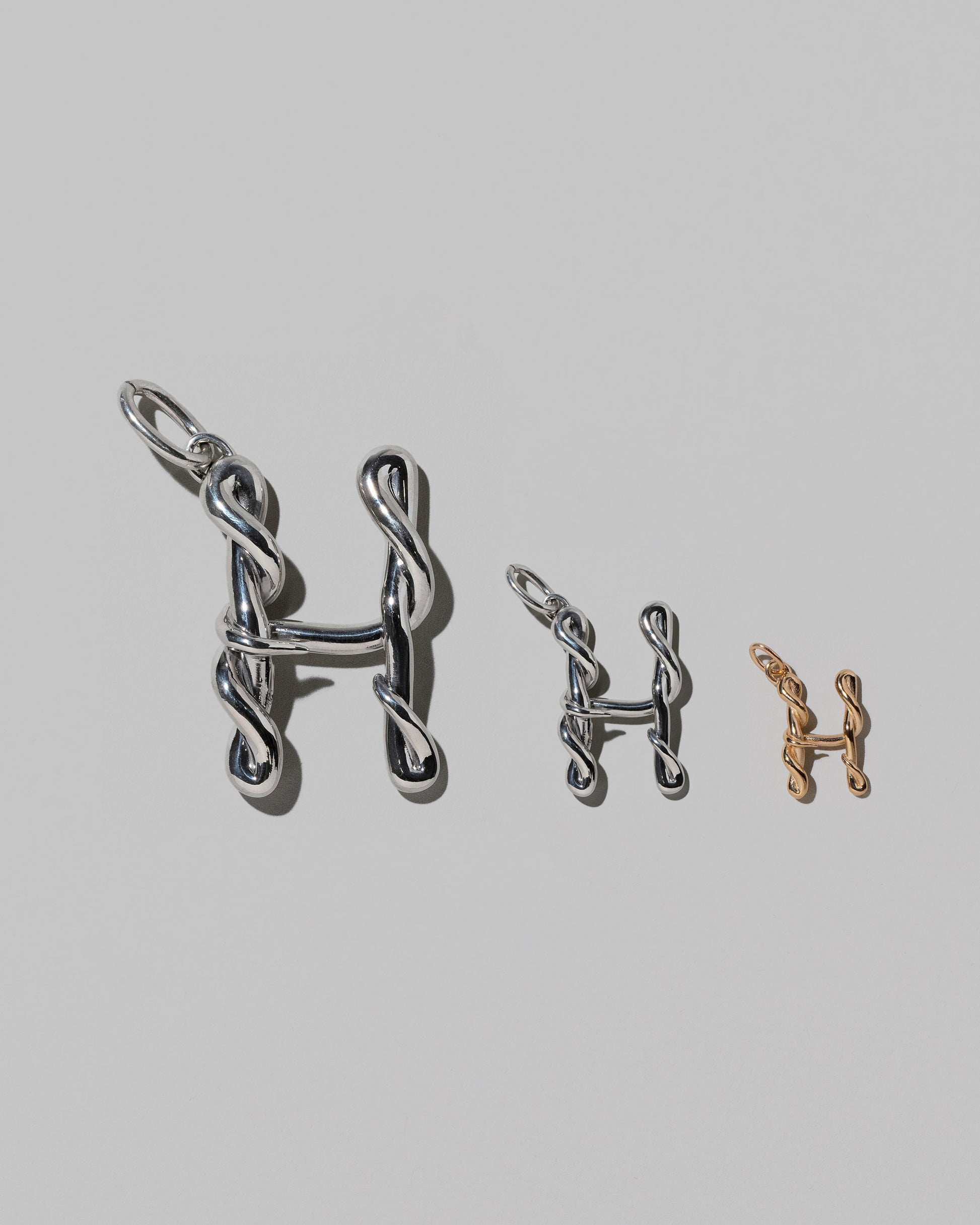 CRZM Large Sterling Silver, Medium Sterling Silver & Mini Letter H Charms set in solid gold on light color background.