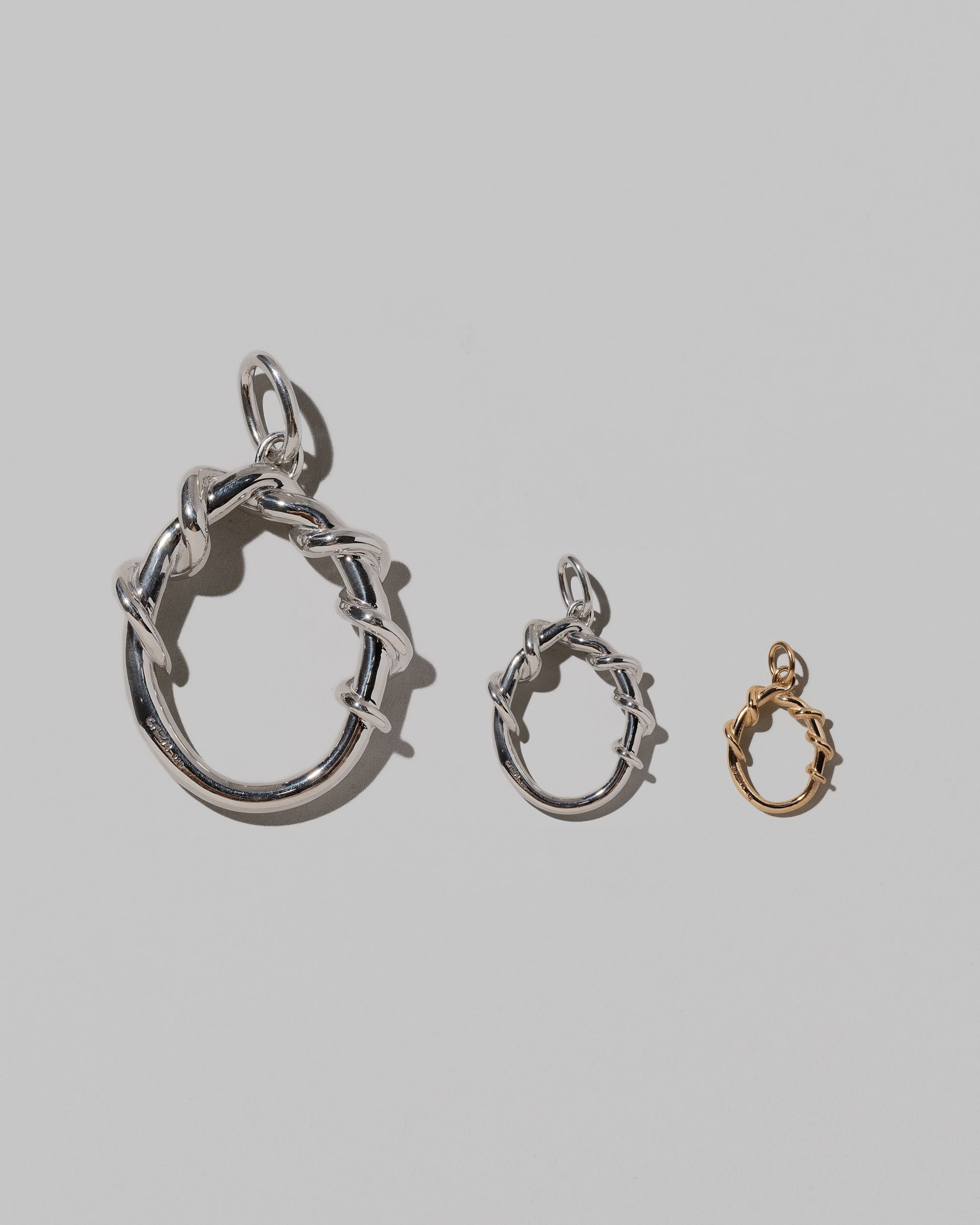 CRZM Large Sterling Silver, Medium Sterling Silver & Mini Letter O Charms set in solid gold on light color background.