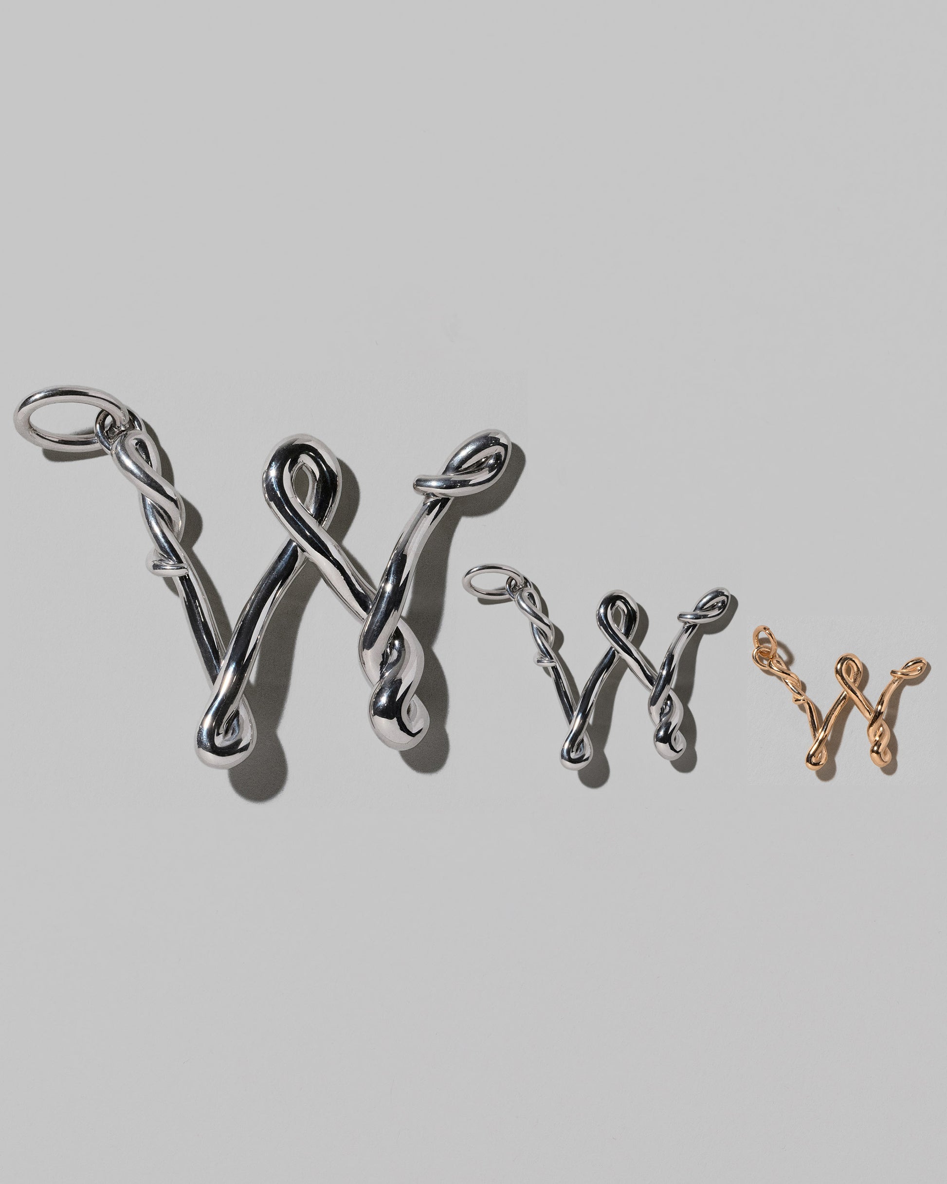 CRZM Large Sterling Silver, Medium Sterling Silver & Mini Letter W Charms set in solid gold on light color background.