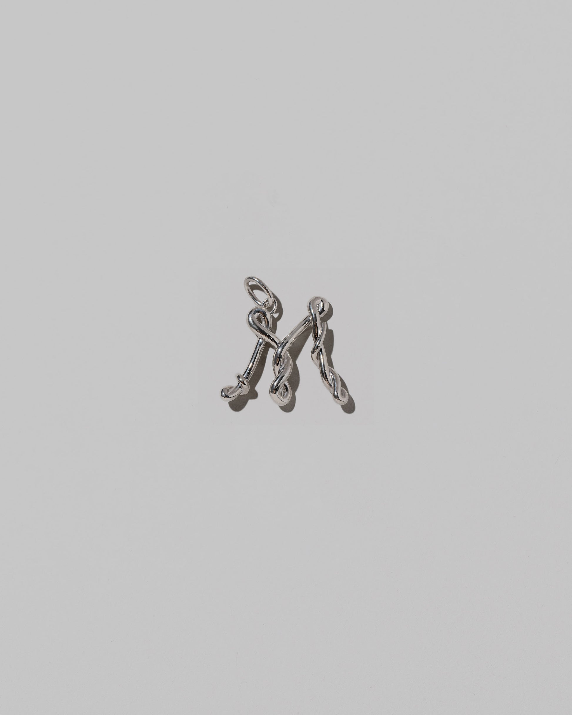 CRZM Medium Letter M Charm set in sterling silver on light color background.