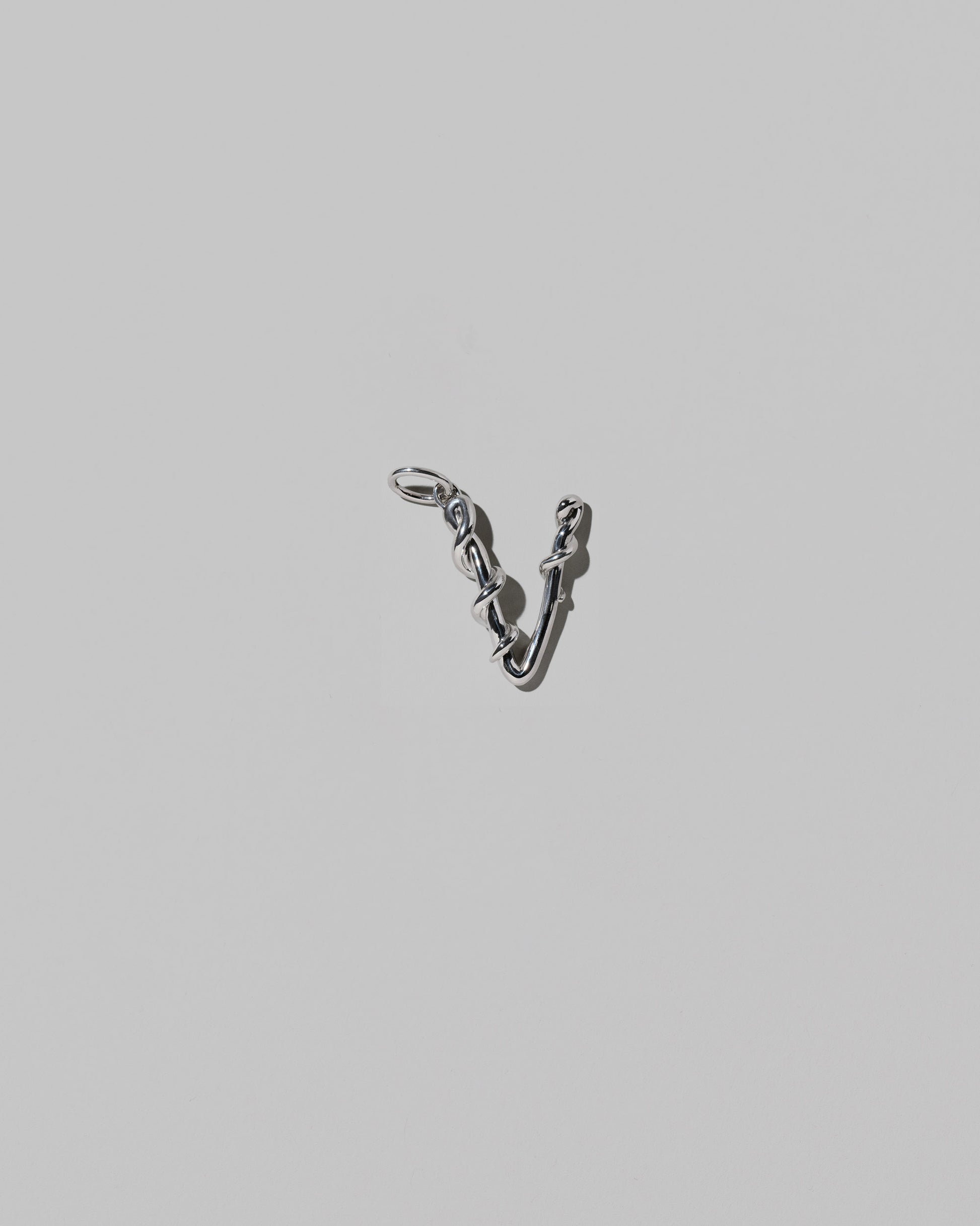 CRZM Medium Letter V Charm set in sterling silver on light color background.