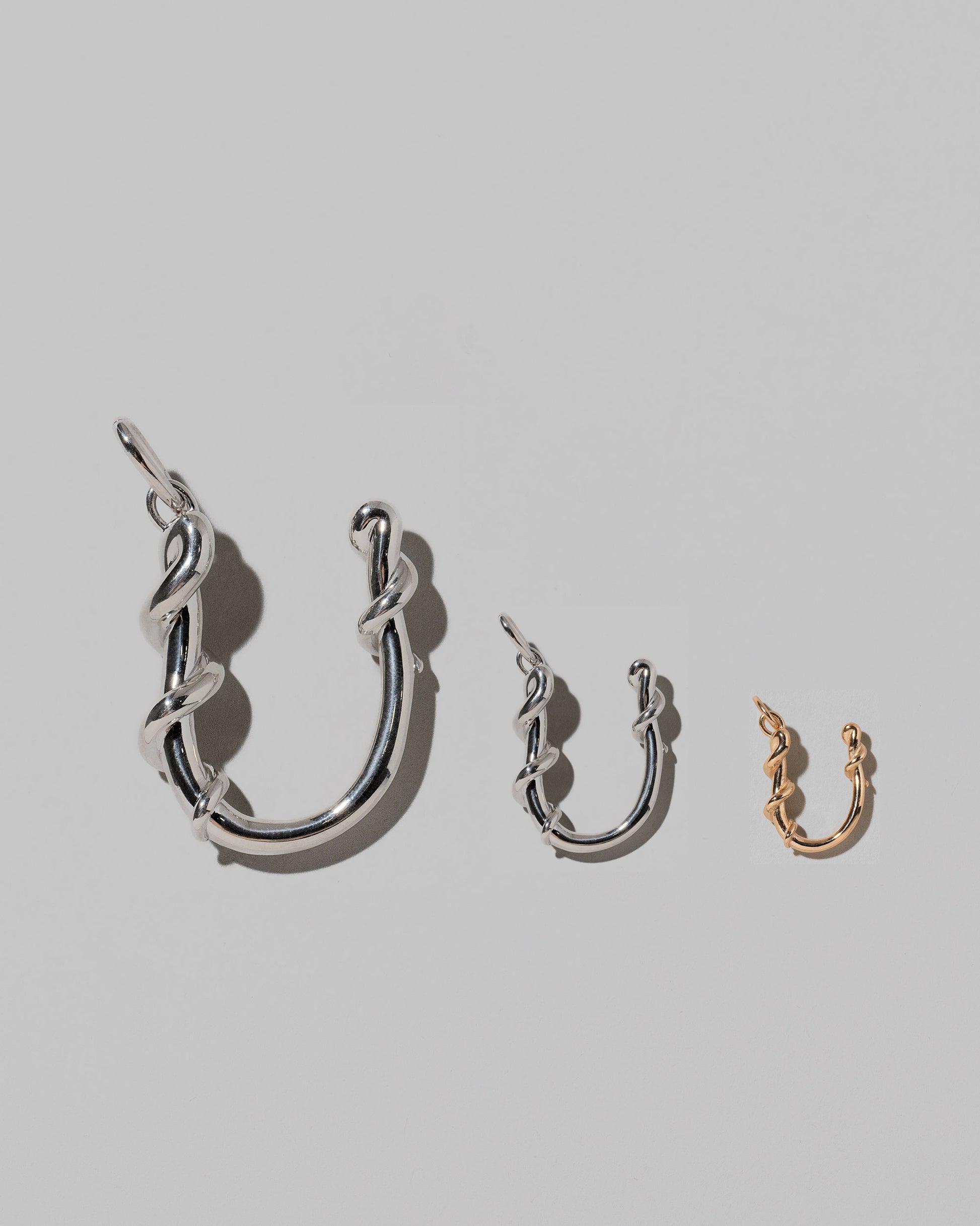 CRZM Large Sterling Silver, Medium Sterling Silver & Mini Letter U Charms set in solid gold on light color background.