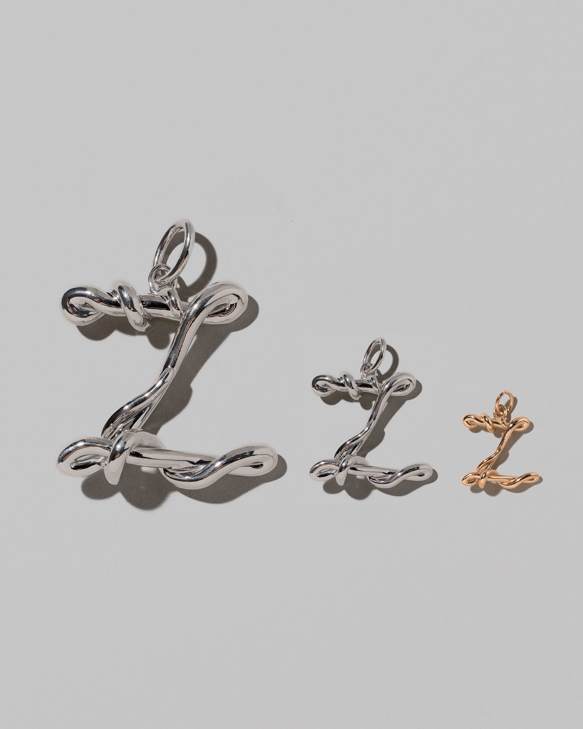 CRZM Large Sterling Silver, Medium Sterling Silver & Mini Letter Z Charms set in solid gold on light color background.