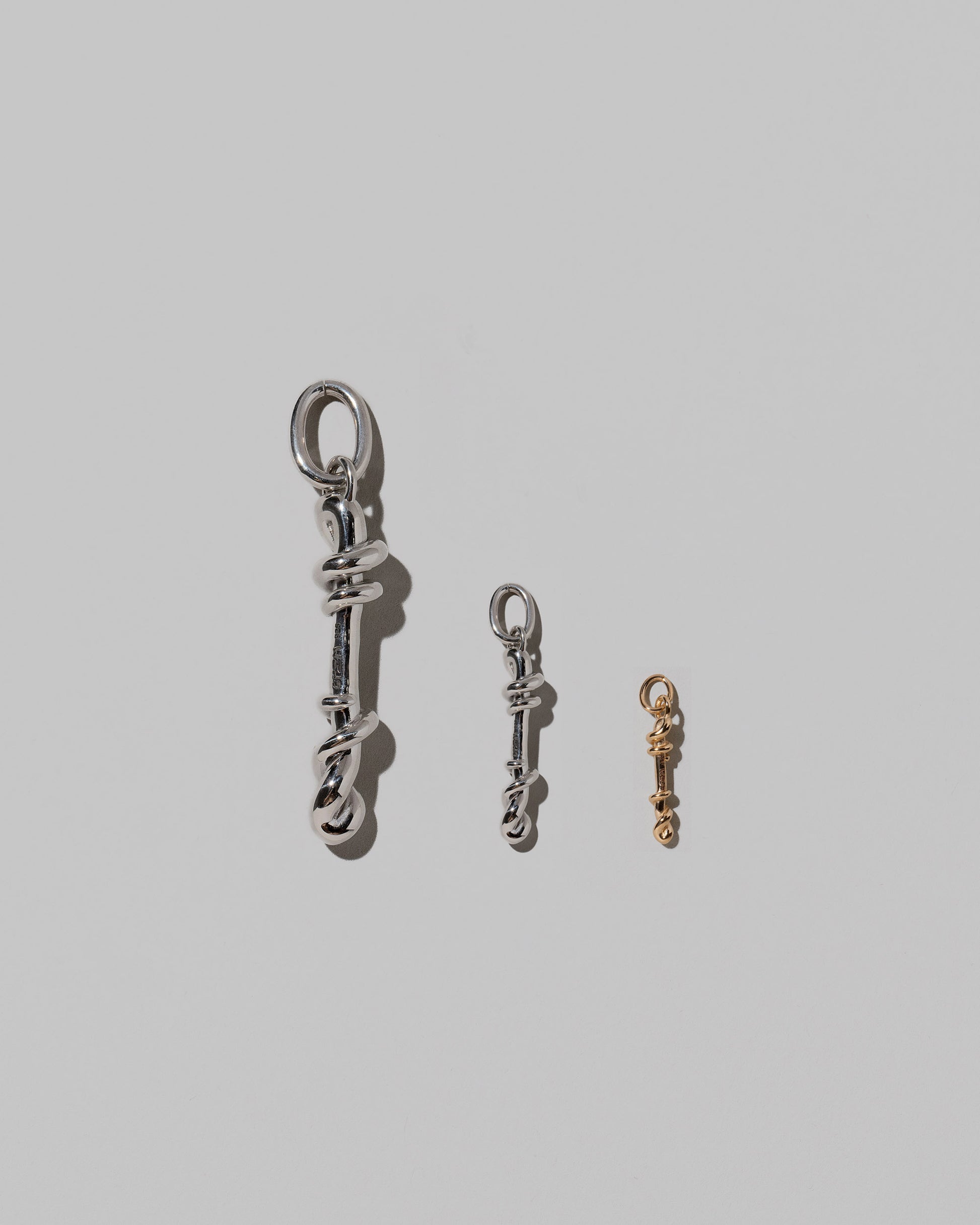 CRZM Large Sterling Silver, Medium Sterling Silver & Mini Letter I Charms set in solid gold on light color background.