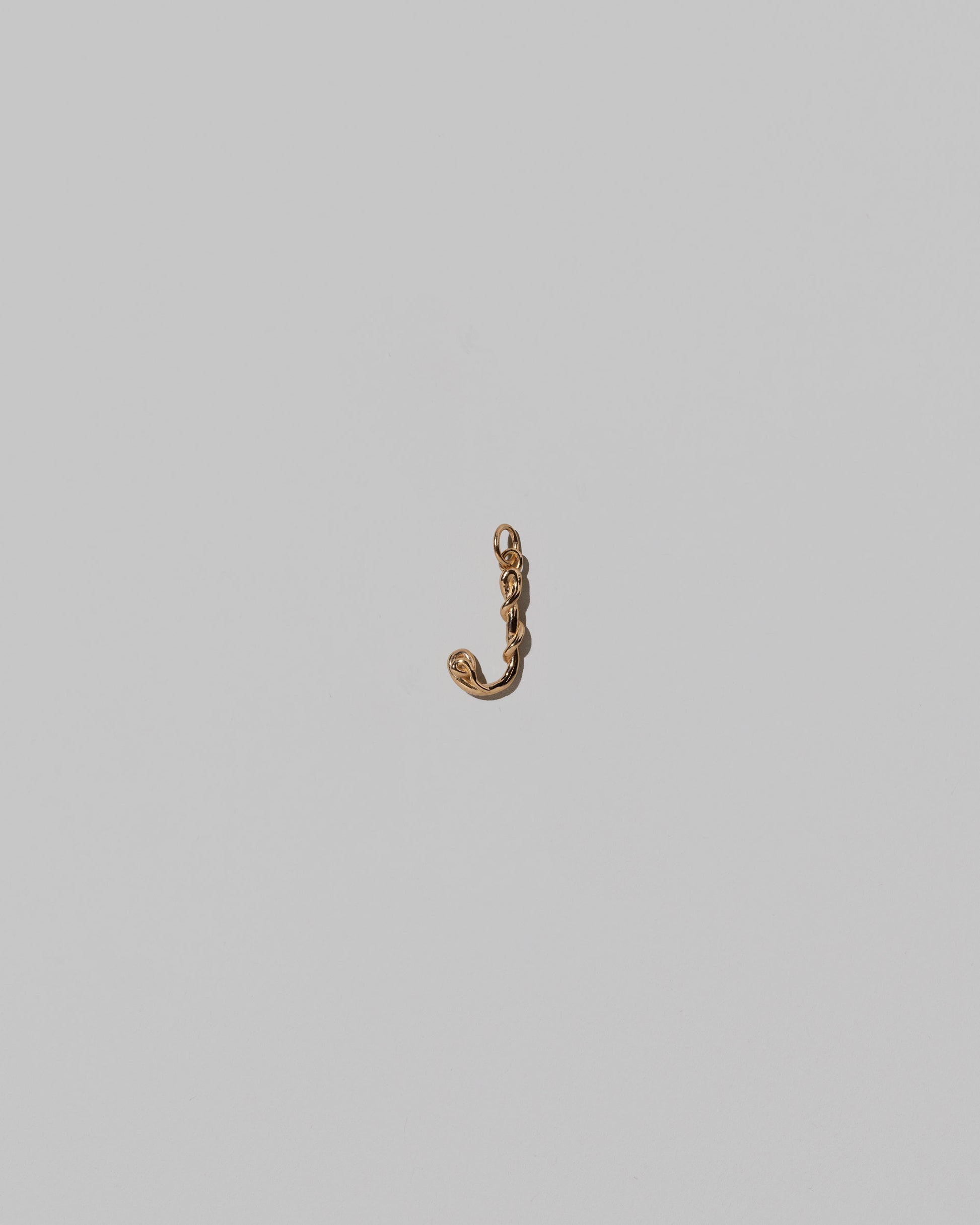 CRZM Mini Letter J set in solid gold on light color background.