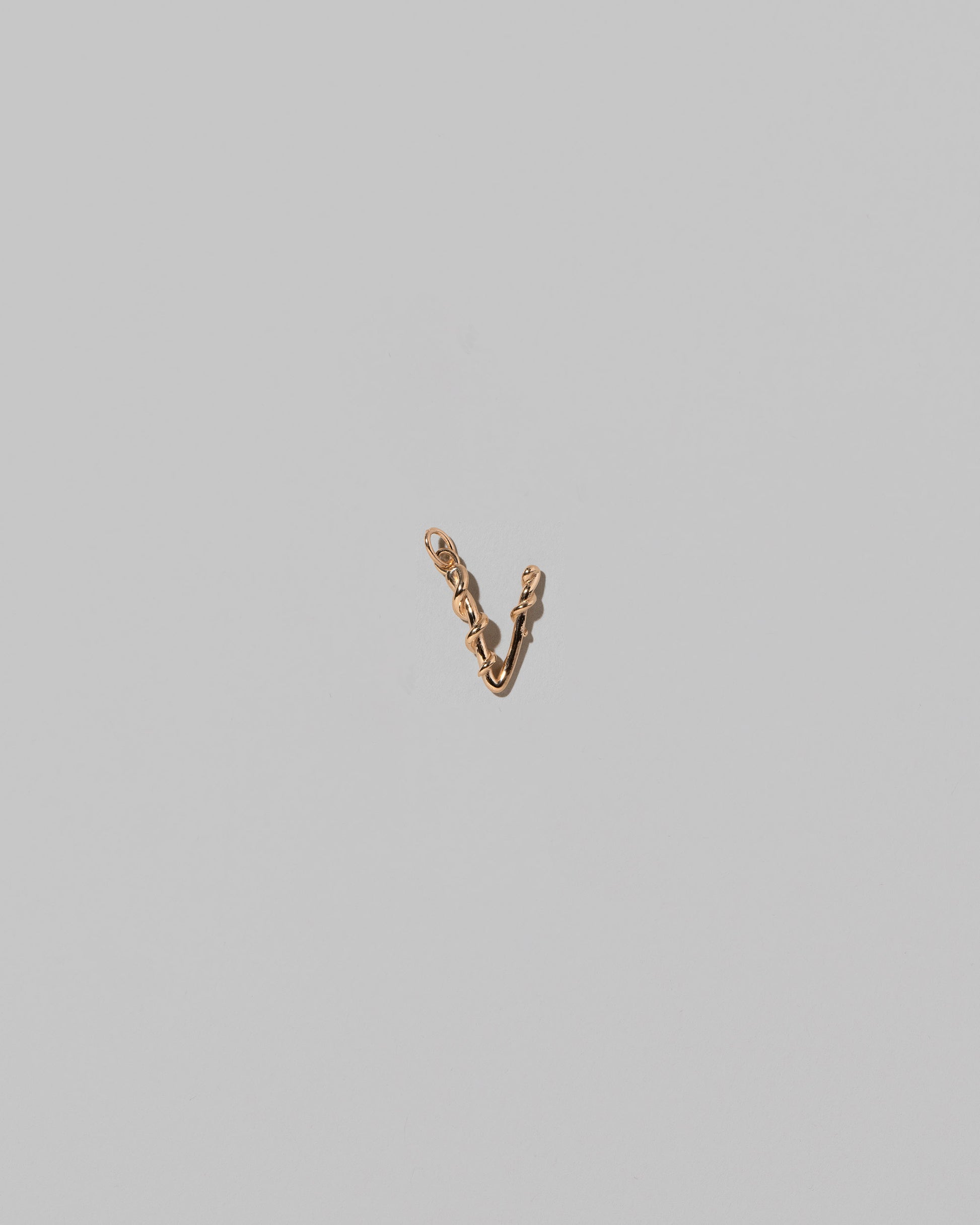 CRZM Mini Letter V set in solid gold on light color background.