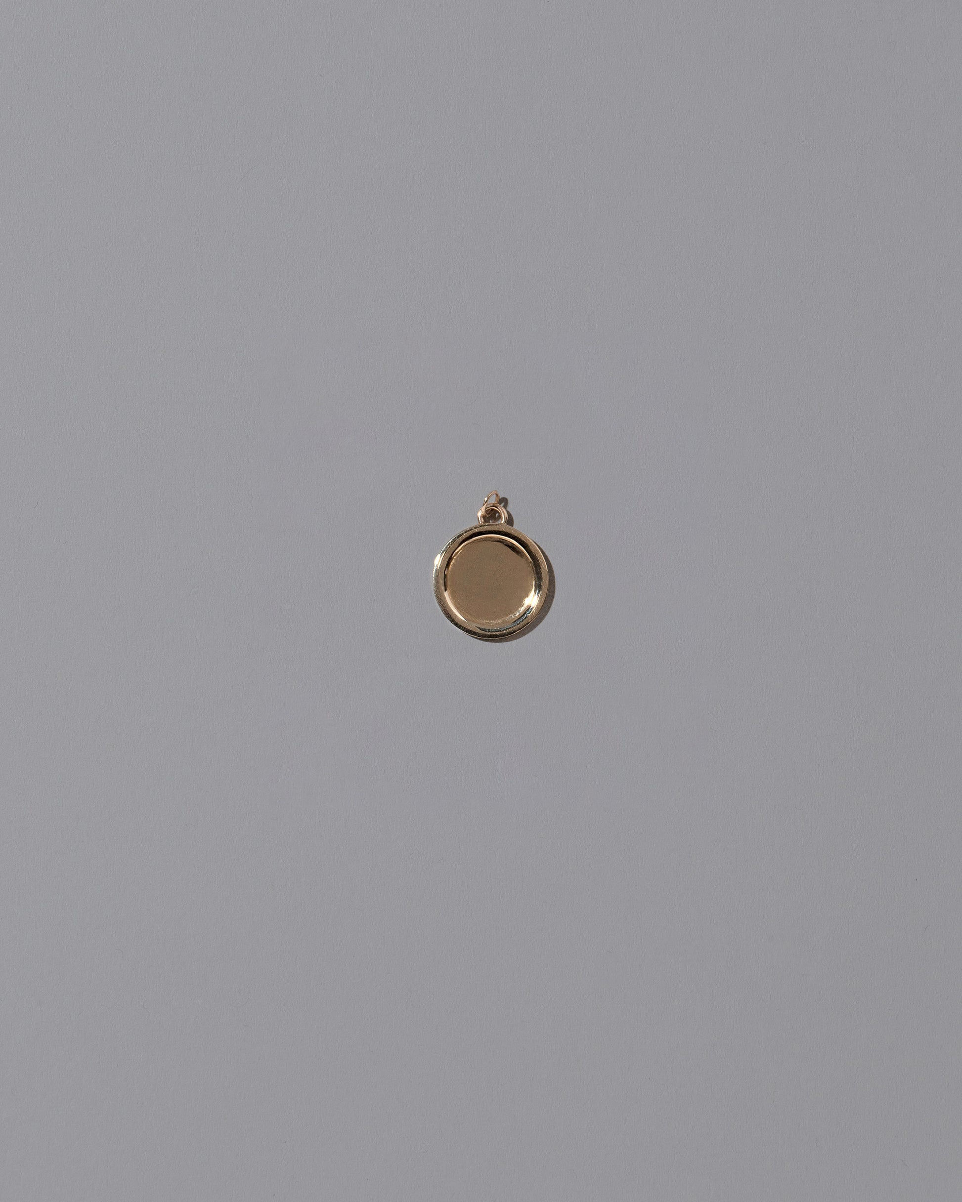 Unfinished Small Round Memento Pendant on light color background.