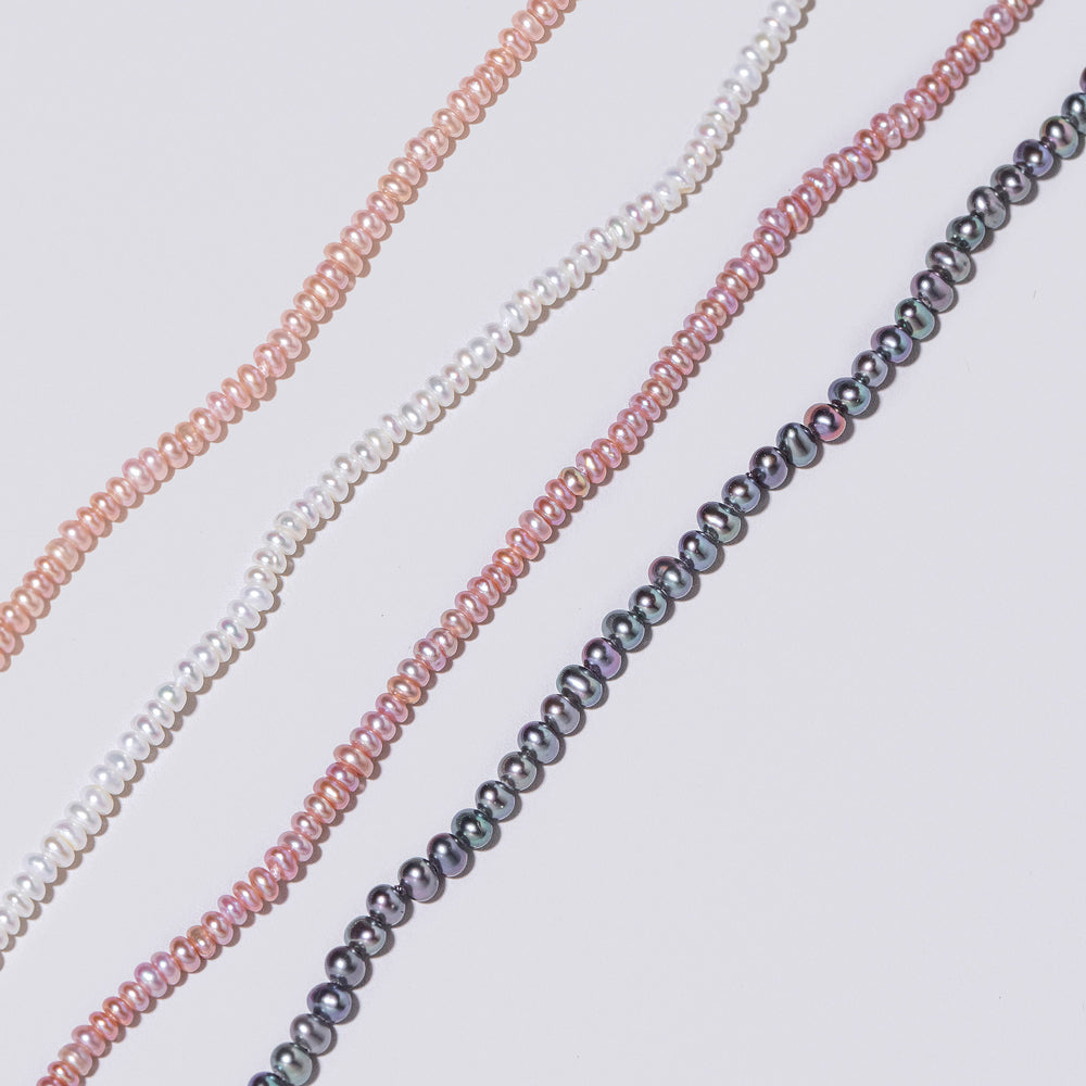 product_details::Closeup details of the Pink Peony Pebble Seed Pearl, White Seed Pebble Pearl Bracelet, Pink Lavender Pebble Seed Pearl Bracelet and Peacock Pebble Seed Pearl Bracelet on light color background.