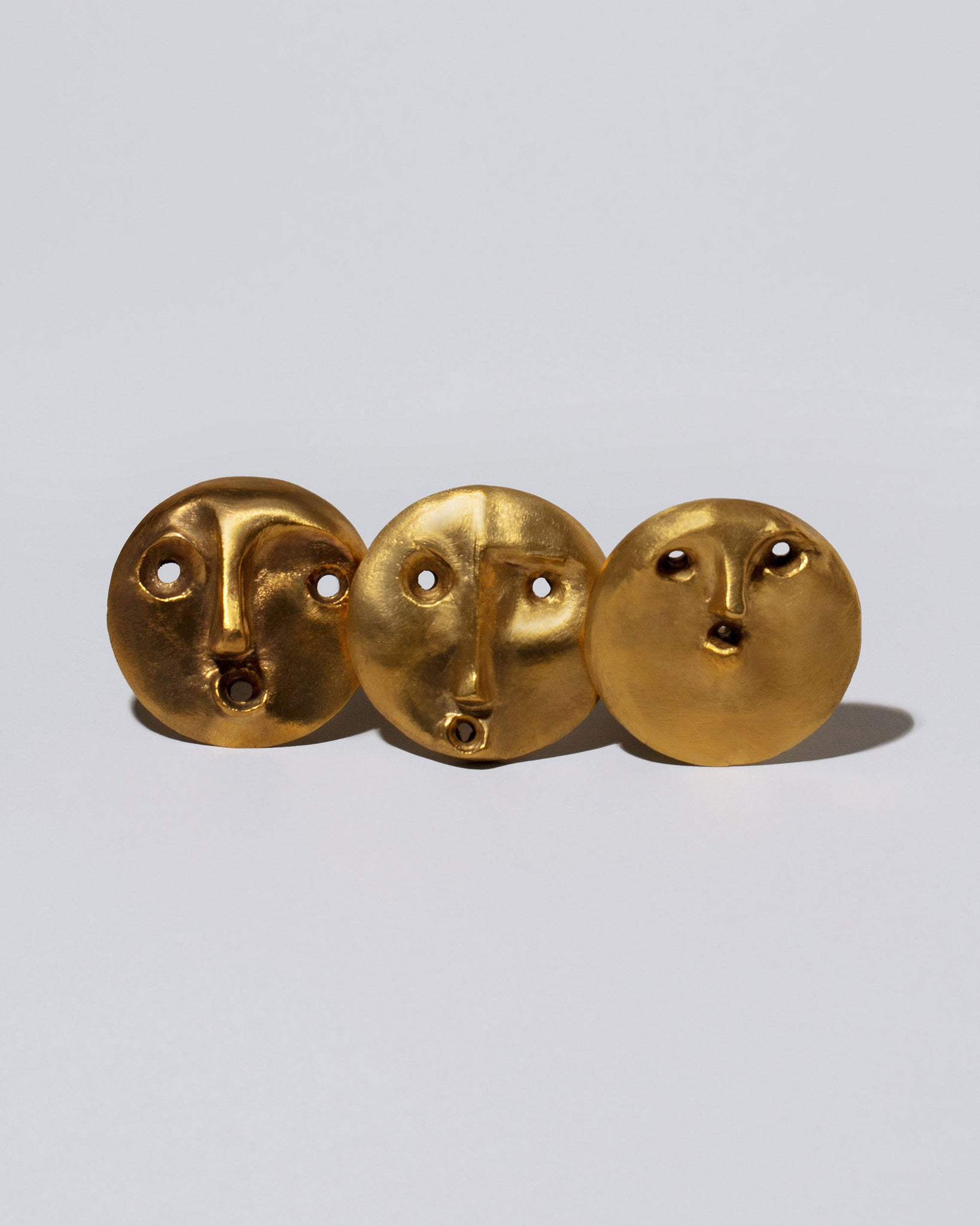 Group of Carl Auböck Peonio, Sambucus and Uranio Brass Face Bottle Stoppers on light color background.