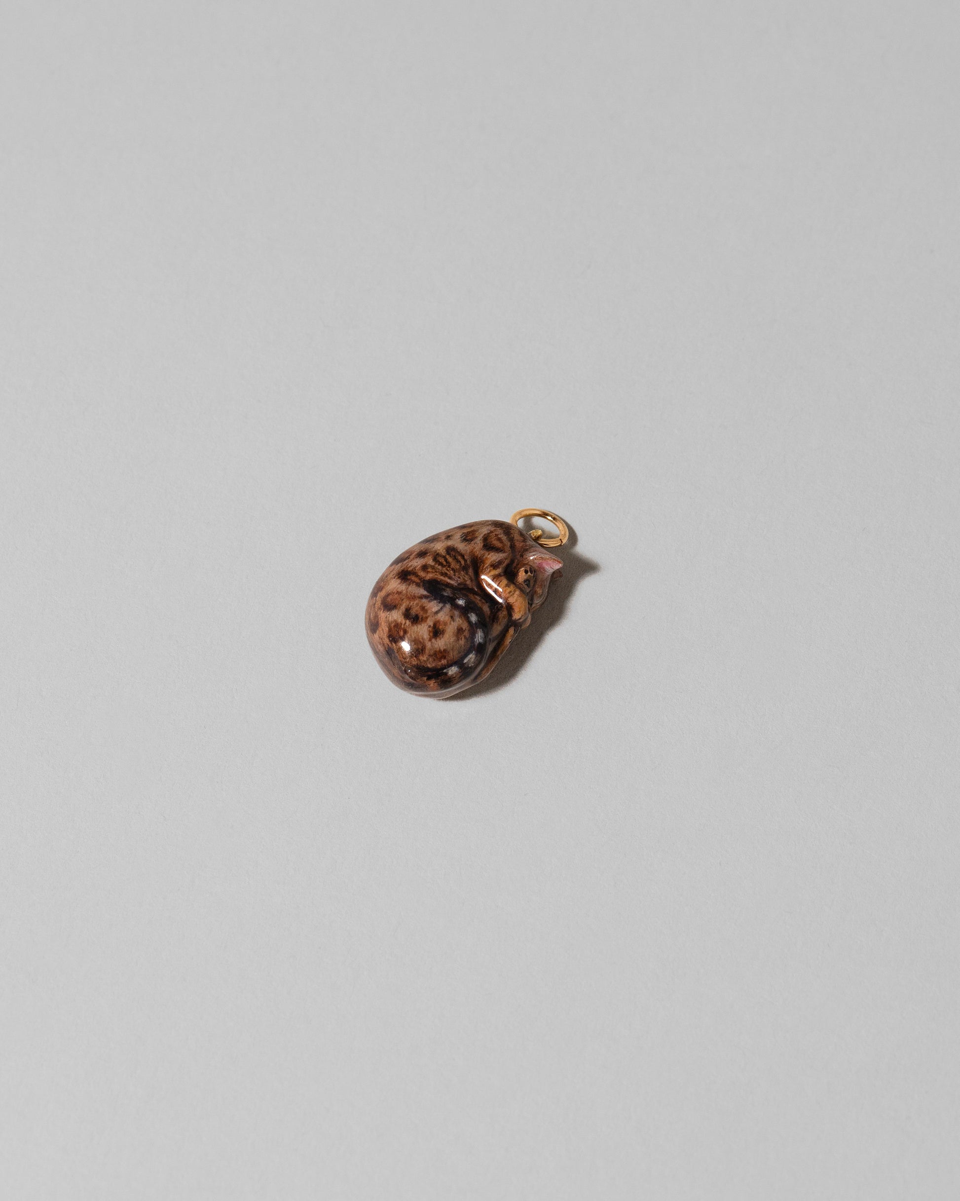 View from the side of the Curled-Up Cat Charm on light color background.