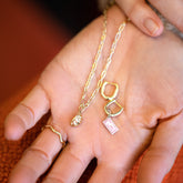 product_details::Hot Dog Chain Necklace with Steamed Dumpling Charm, Dumpling Sauce Packet Charm paired with the Huggie components of the Solid Gold Link Huggie Hoop Earrings and Gold Bump Band on model.