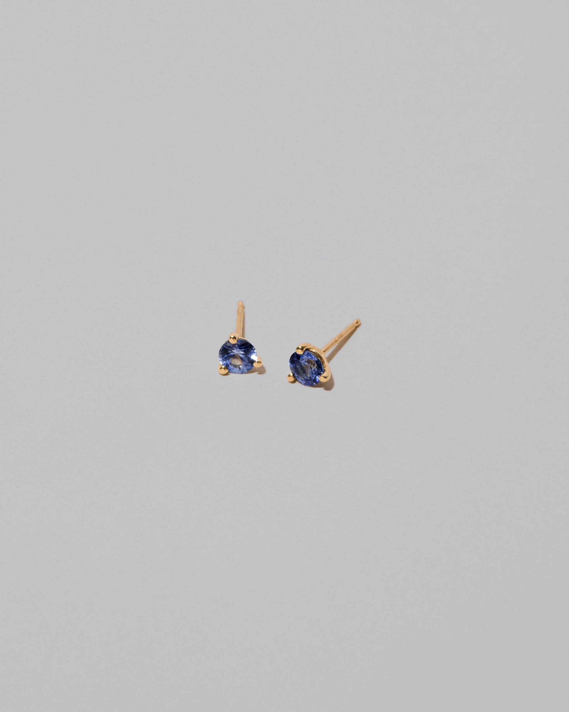 Bicolor Blue Sapphire Martini Stud Earrings on light color background.