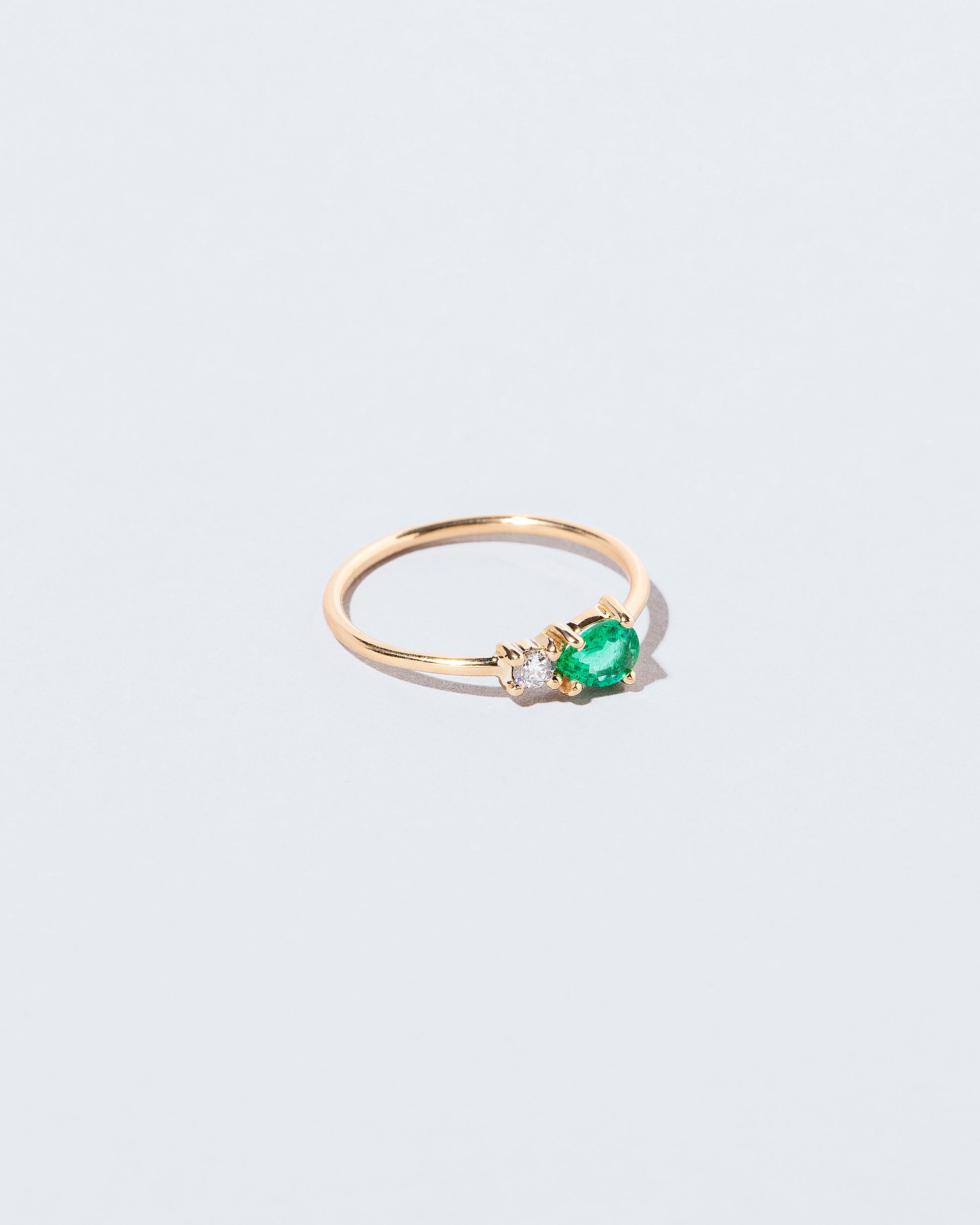 View from the side of the Emerald & Diamond Teardrop Ring on light color background.