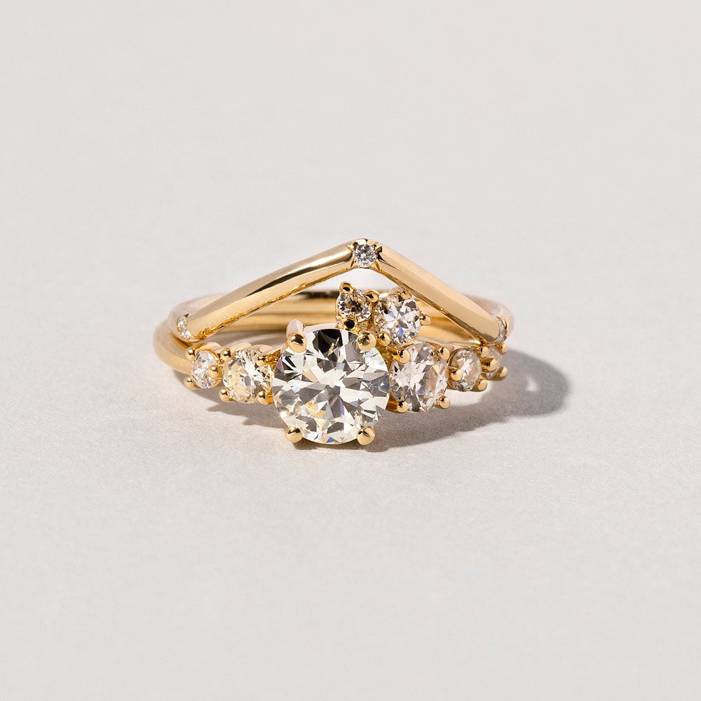 product_details::Closeup detail of the Luna Ring and White Diamond Three Stone Yellow Gold Luna Peak Band on light color background.