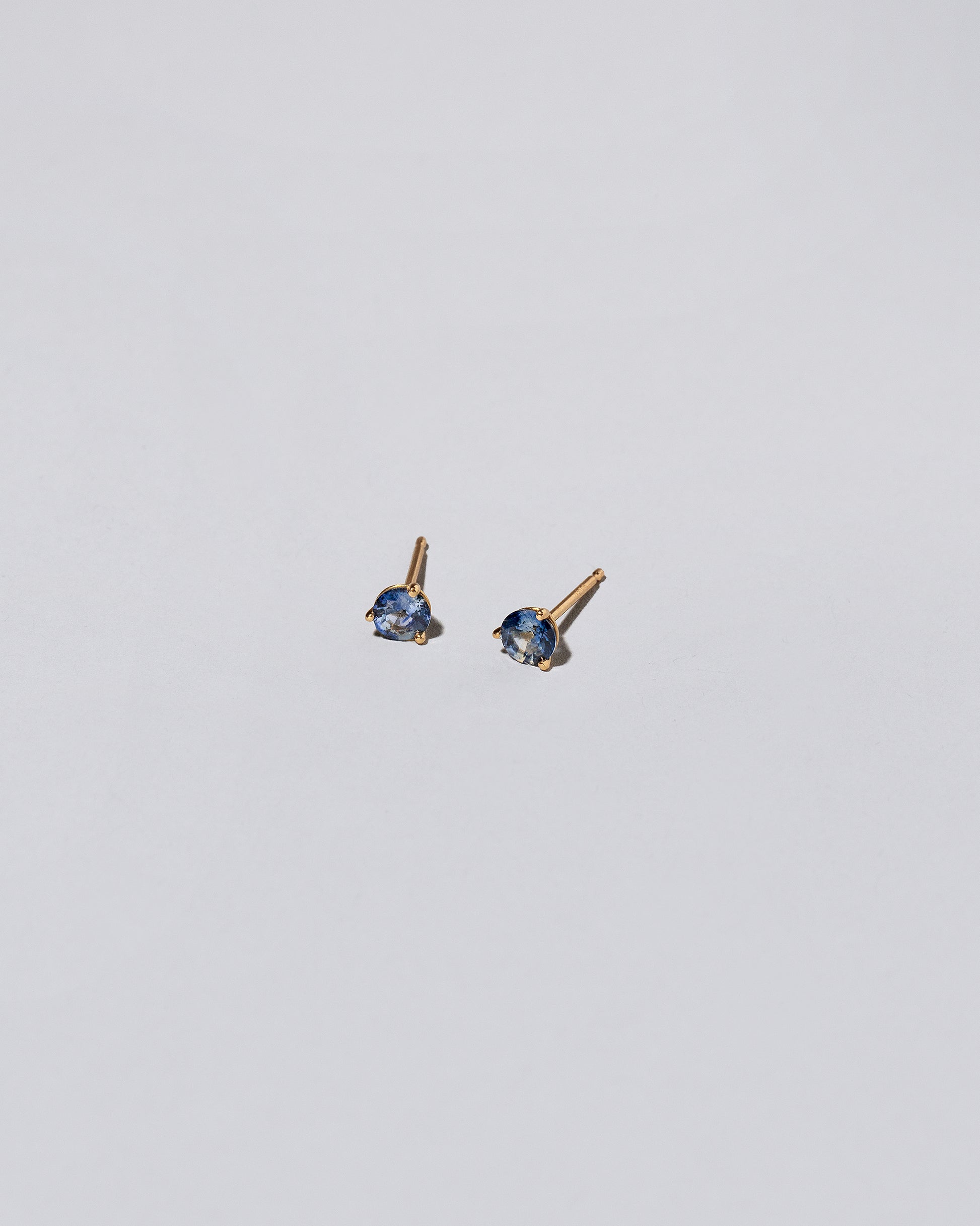 Blue Bicolor Sapphire Martini Stud Earrings on light color background.