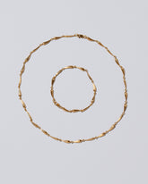 Gold Accumulation Necklace & Bracelets Set on light color background.
