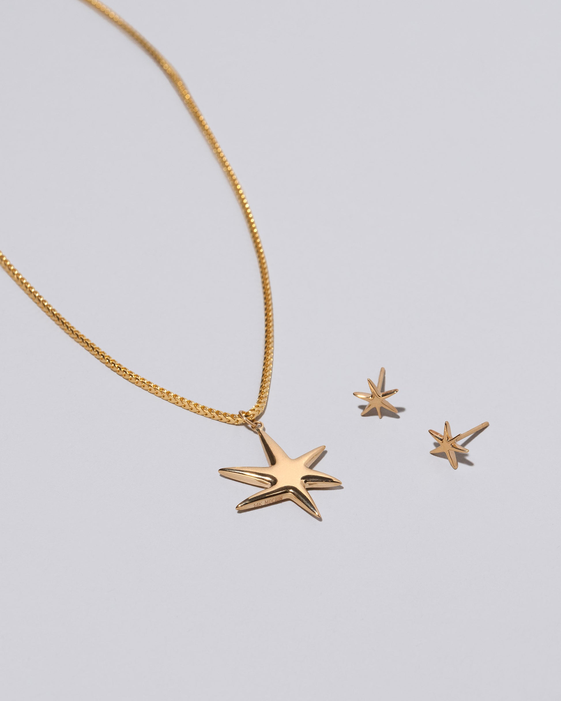 Gold Stars Necklace & Studs Set on light color background.