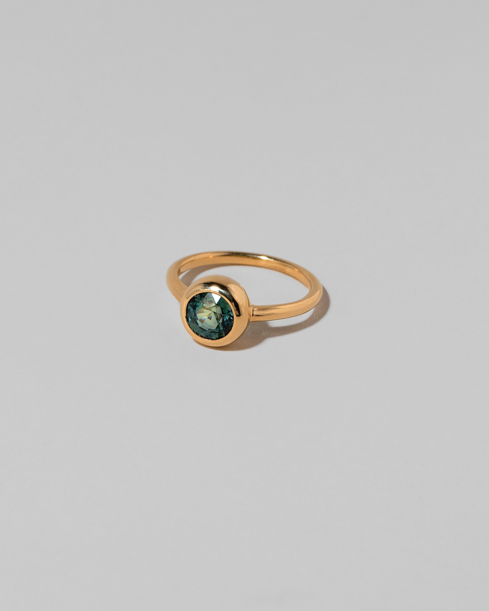 View from the side of the Teal Sapphire Wellspring Ring on light color background.