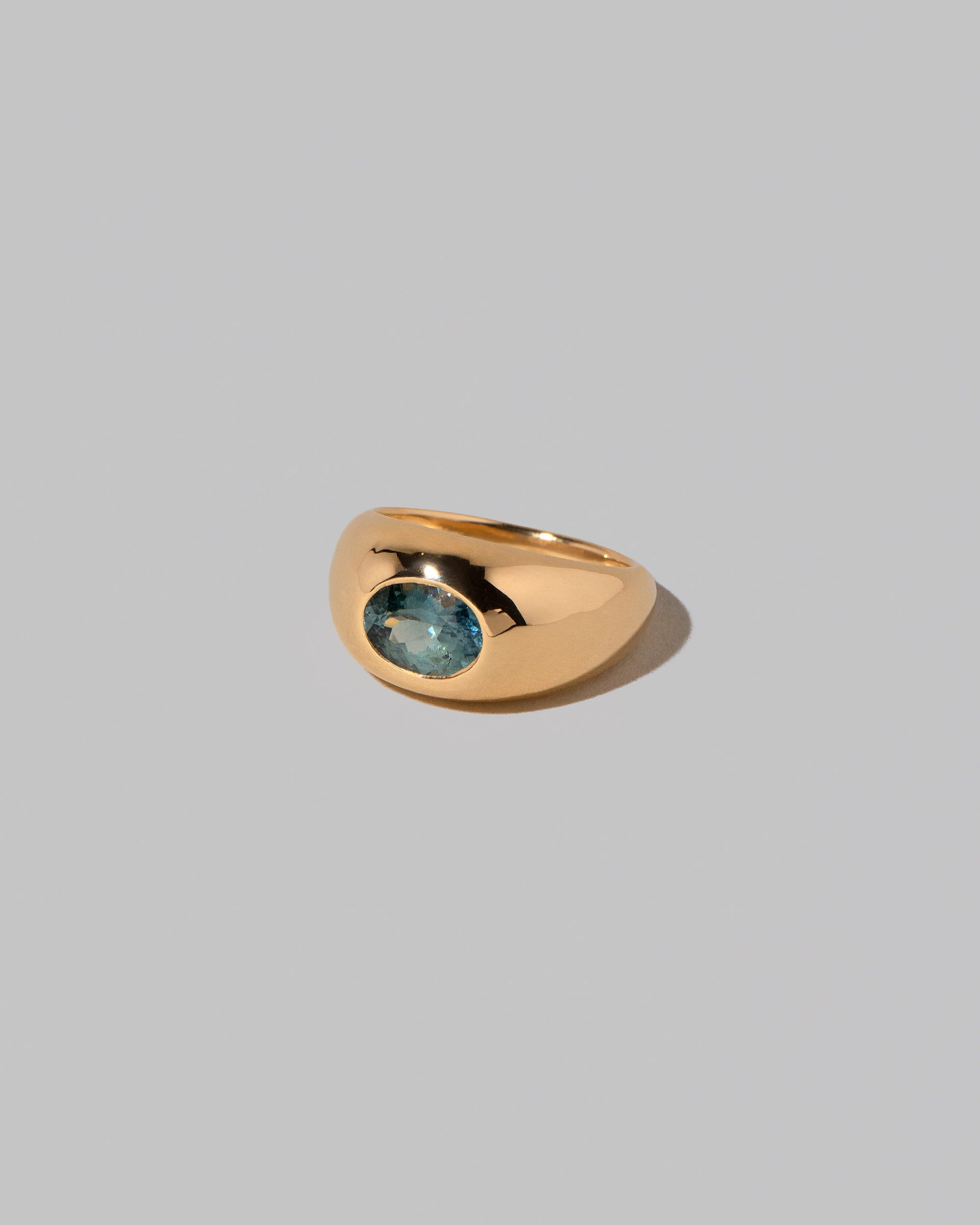 View from the side of the Teal Sapphire Jupiter Ring on light color background.