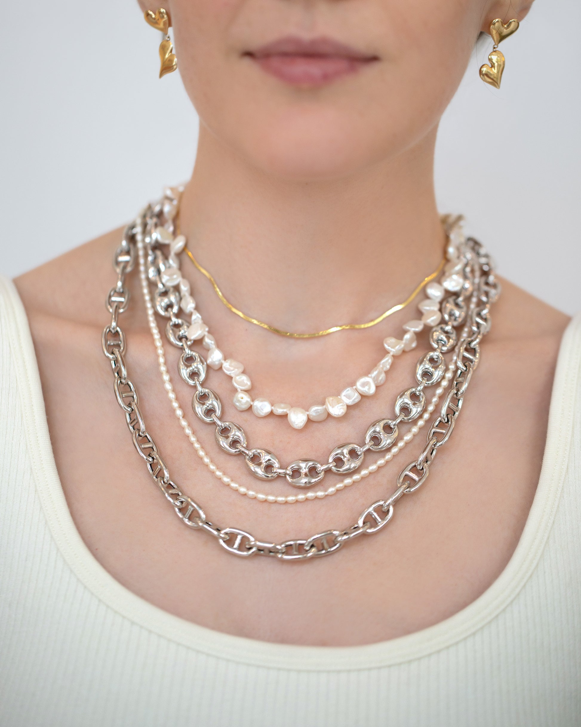 Thousand & One Night Heart Drop Earrings, 1.5mm Liquid Chain Necklace, Silver Puffed Mariner Chain, White Seed Pearl Necklace and Silver Lite Anchor Chain on model.