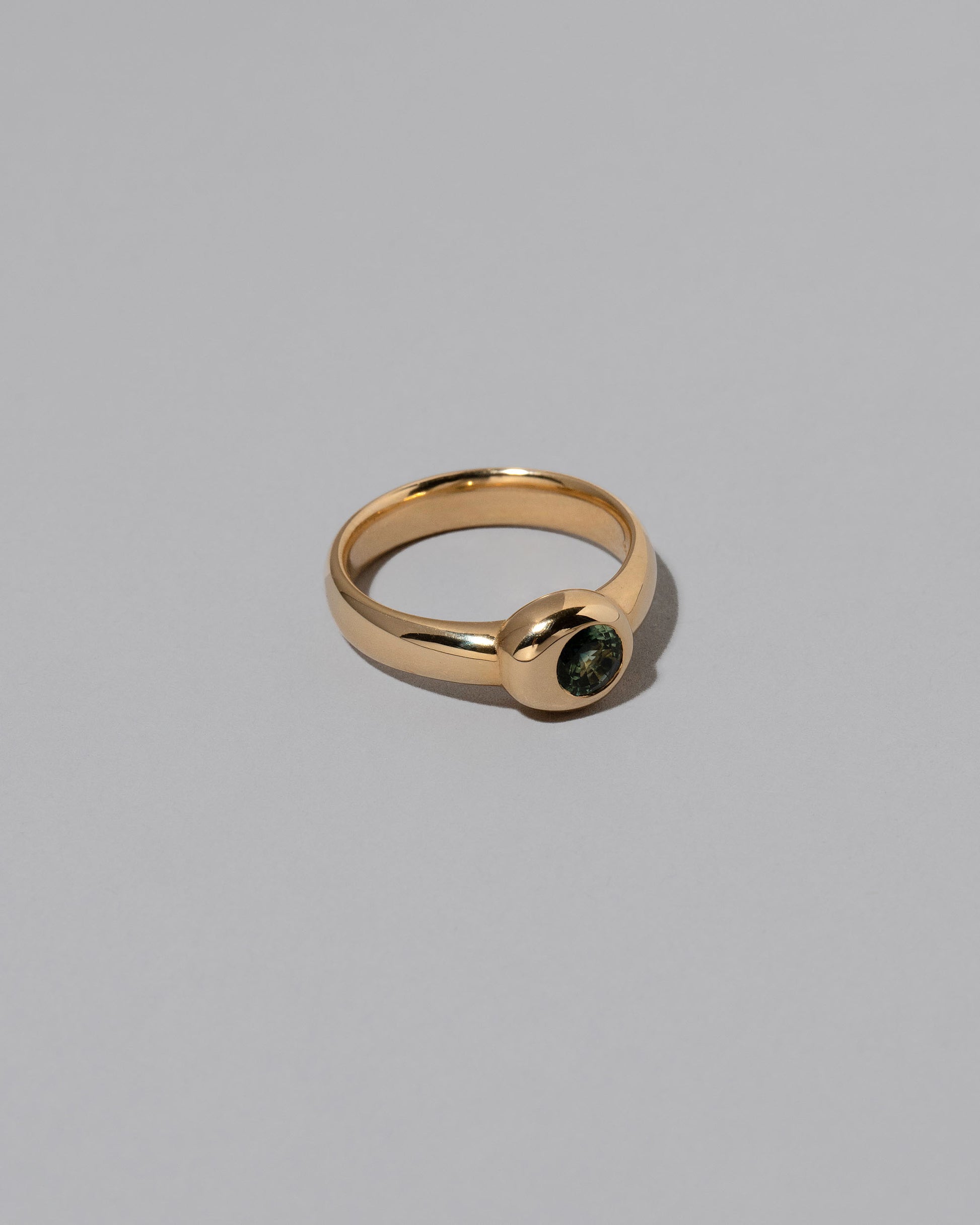 View from the side of the Green Sapphire Level Ring on light color background.