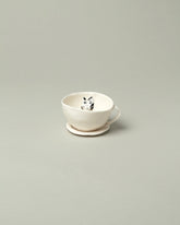 Eleonor Boström Black Spots Cat Tea Cup with Saucer on light color background.