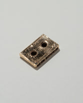 Closeup details of the Pearce Objects Cast Bronze Mini Cassette Tape on light color background.