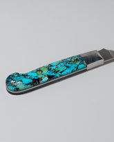 Closeup details of the Santa Fe Stoneworks Kingmen Turquoise Bread Knife on light color background.