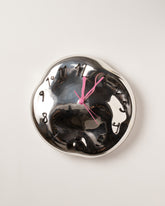 Silje Lindrup Pink Hands Black Glass Wall Clock on light color background.