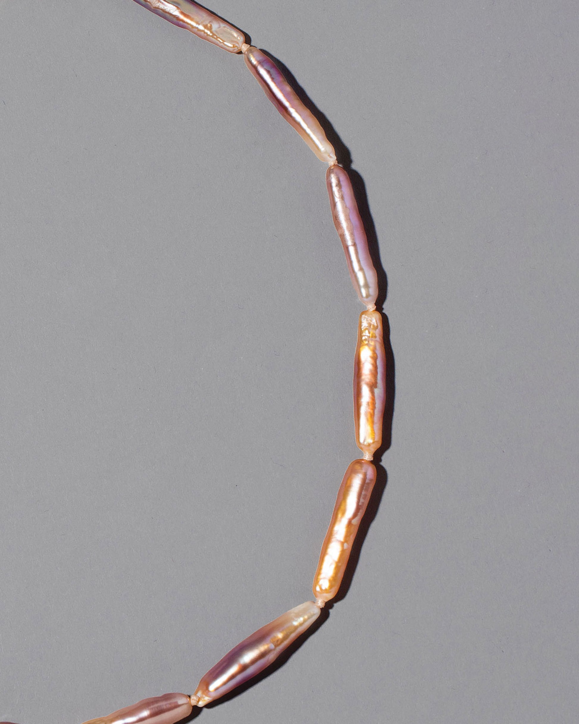 Closeup detail of the Blush Stick Pearl Strand Necklace on grey color background.