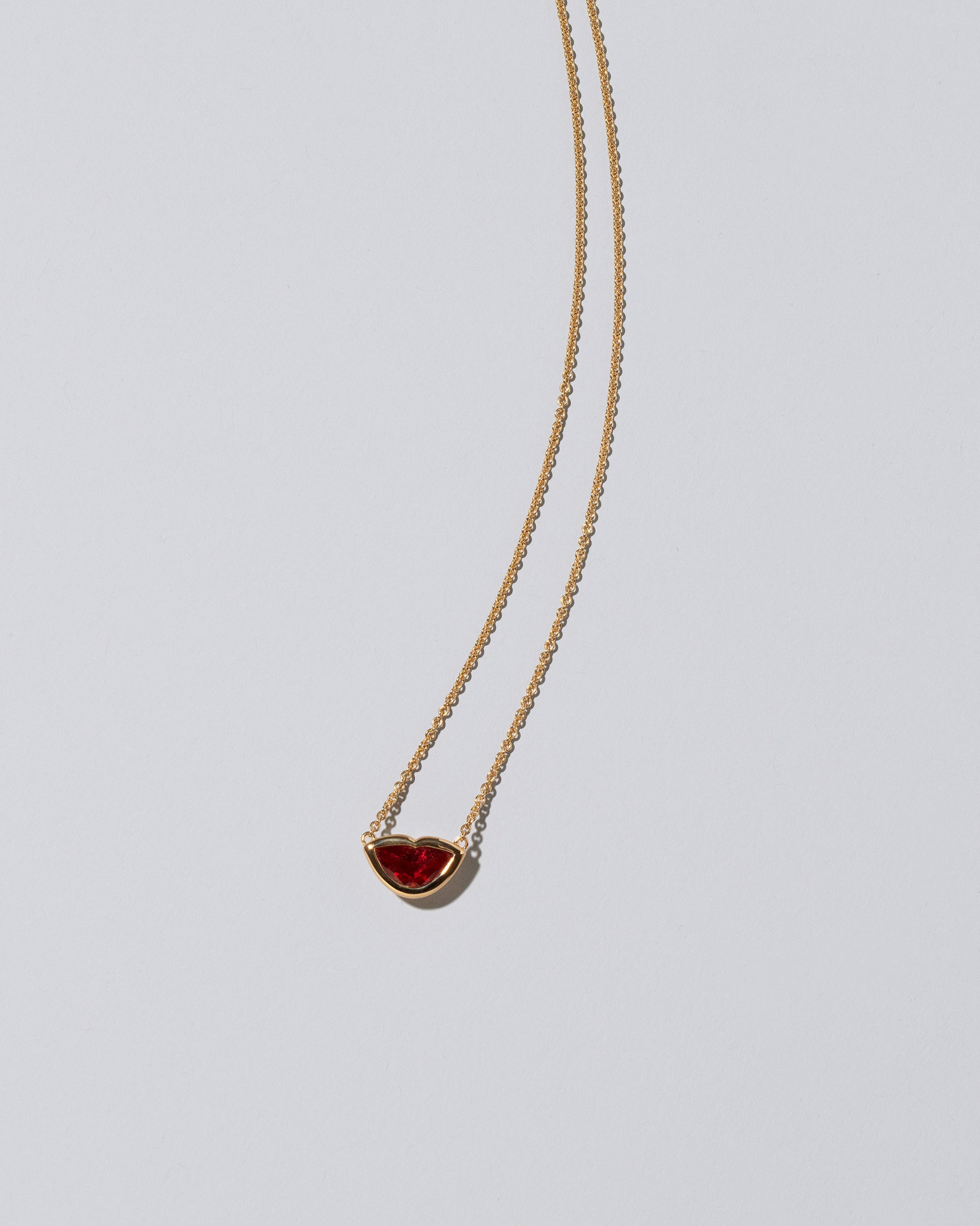 Closeup detail of the Red Spinel Lover's Kiss Necklace on light color background.